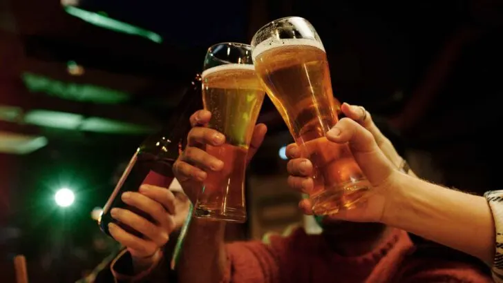 Two beer bottles raised in a sunset toast