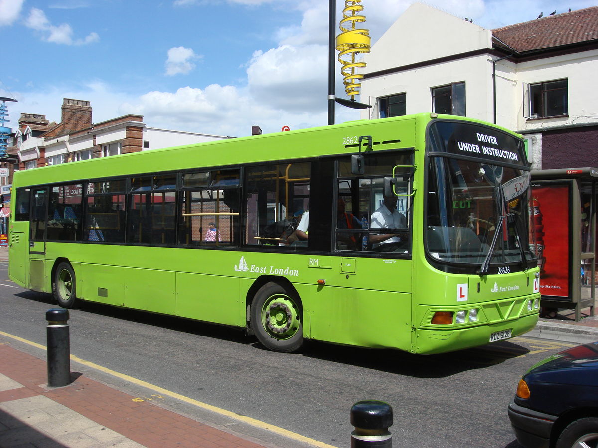 Green public bus traveling along a street in East London