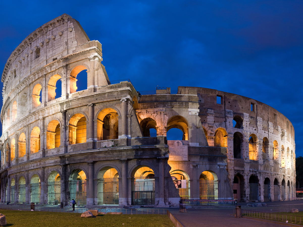The illuminated Colosseum in Rome beneath a deep blue evening sky