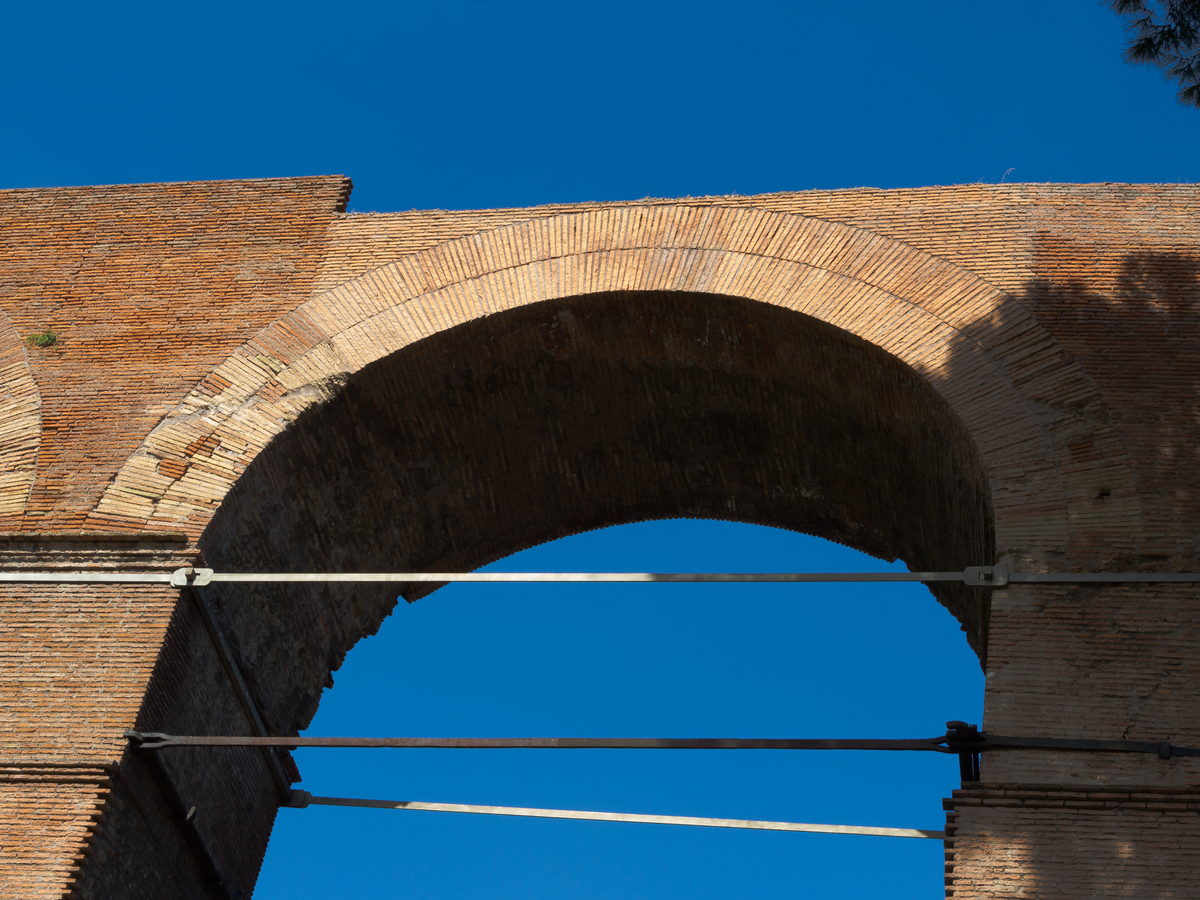 Ancient brick arch in the Roman Forum beneath a clear blue sky