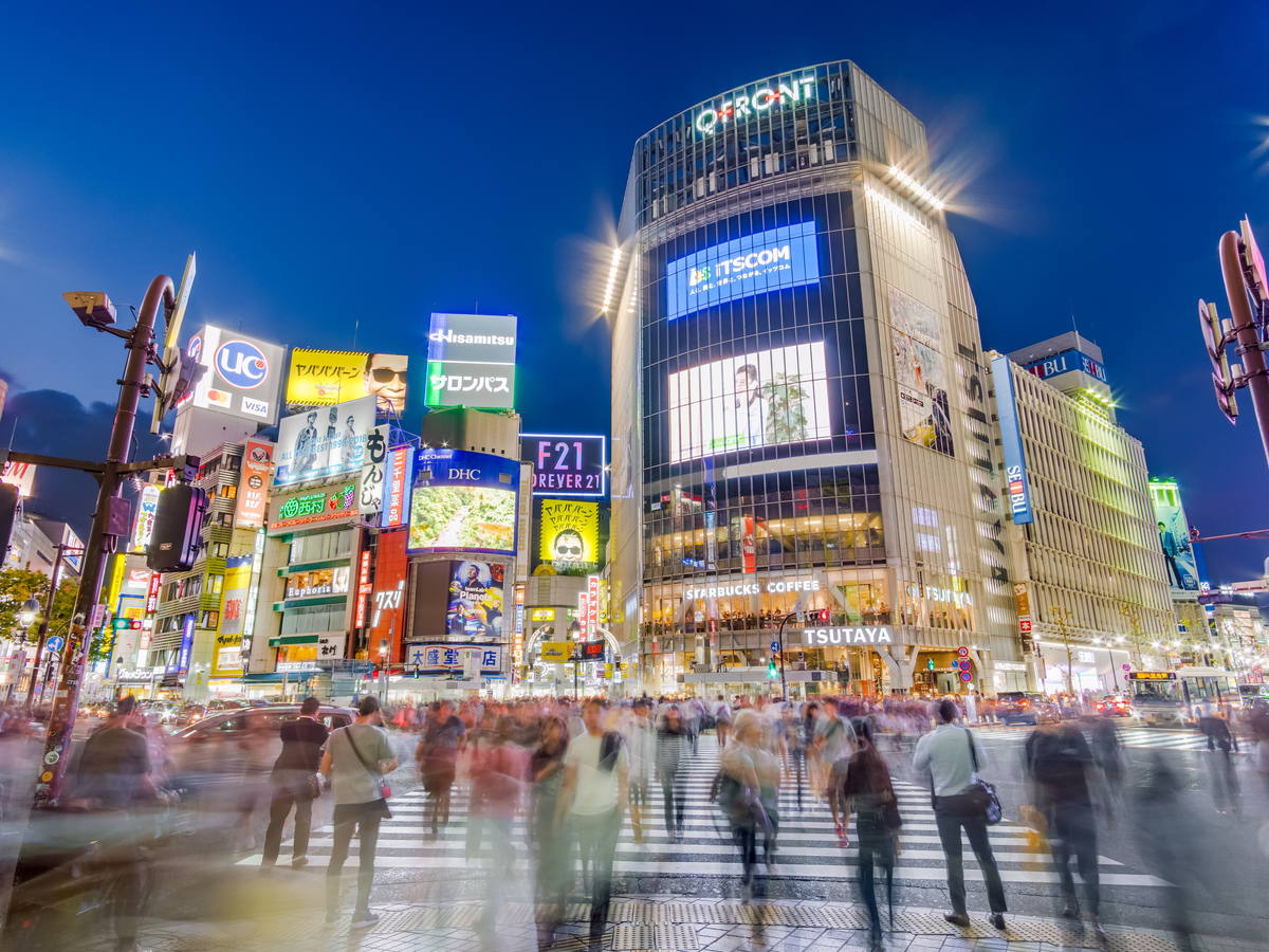 Pedestrians crossing the brightly lit Shibuya intersection in Tokyo