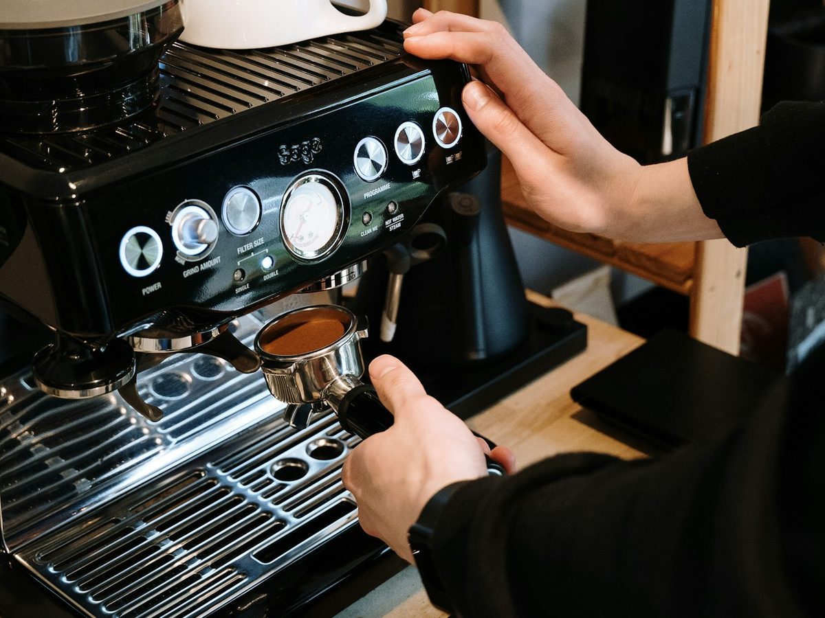 Barista operating the controls of a professional espresso machine