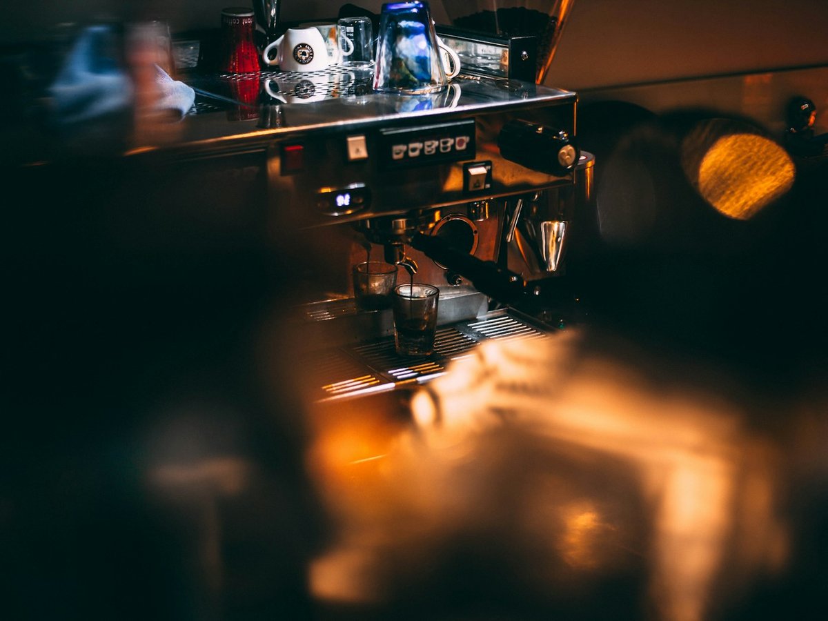 Barista working at an espresso machine behind a cafe counter
