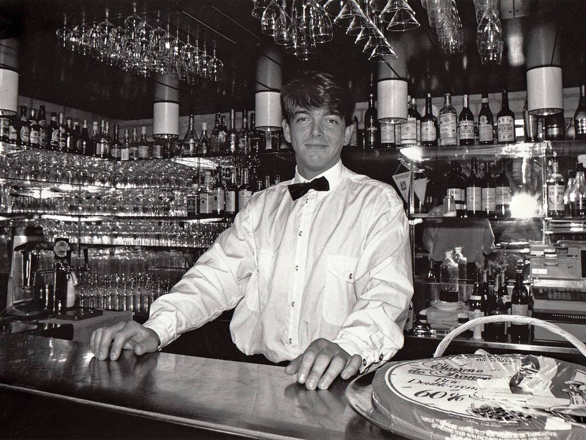 Bartender standing behind a well-stocked bar counter