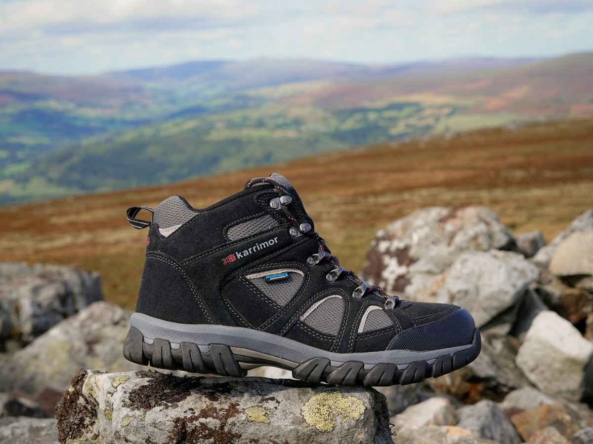 Black hiking boot displayed against a mountain landscape