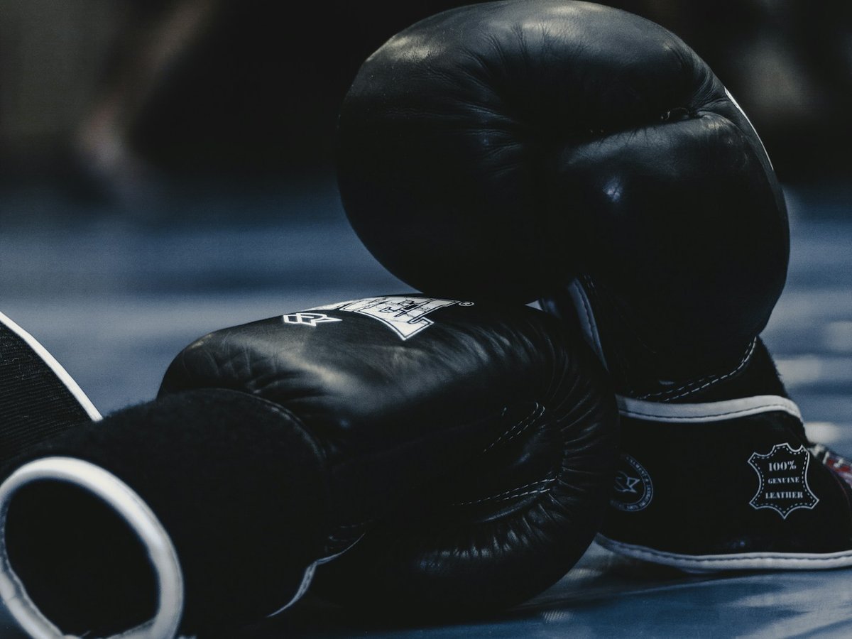 Pair of black boxing gloves resting on a gym floor