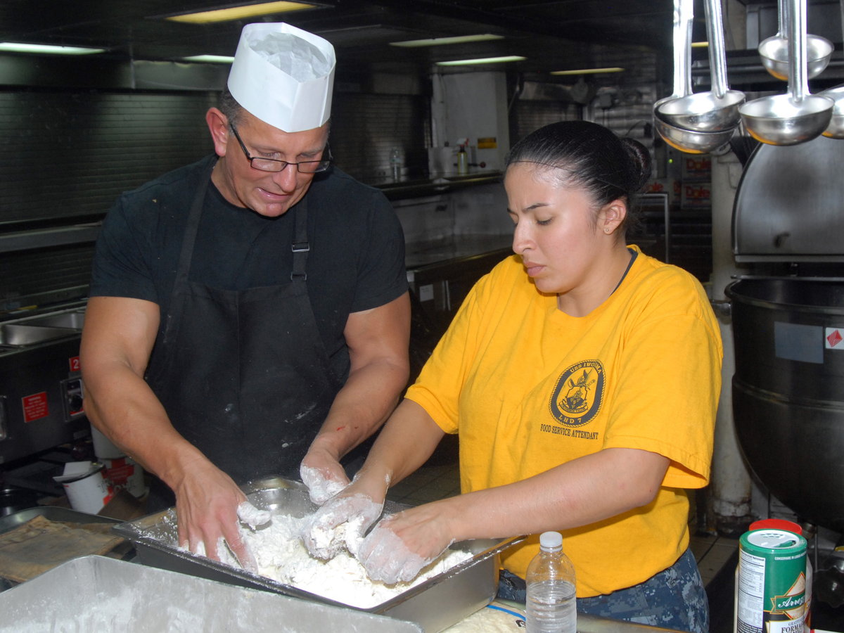 Chef teaching a student how to prepare dough