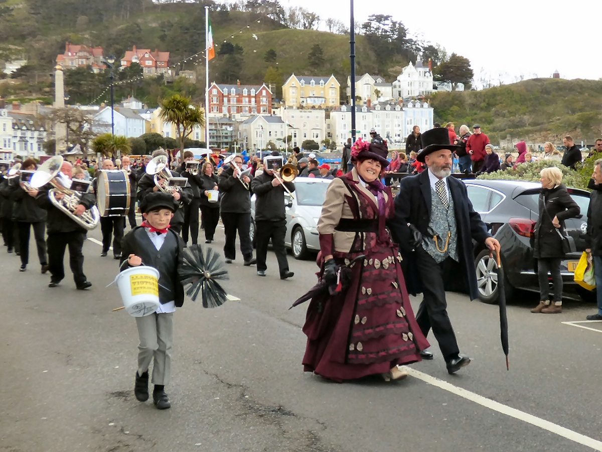Chimney sweep in traditional attire walking with a long brush