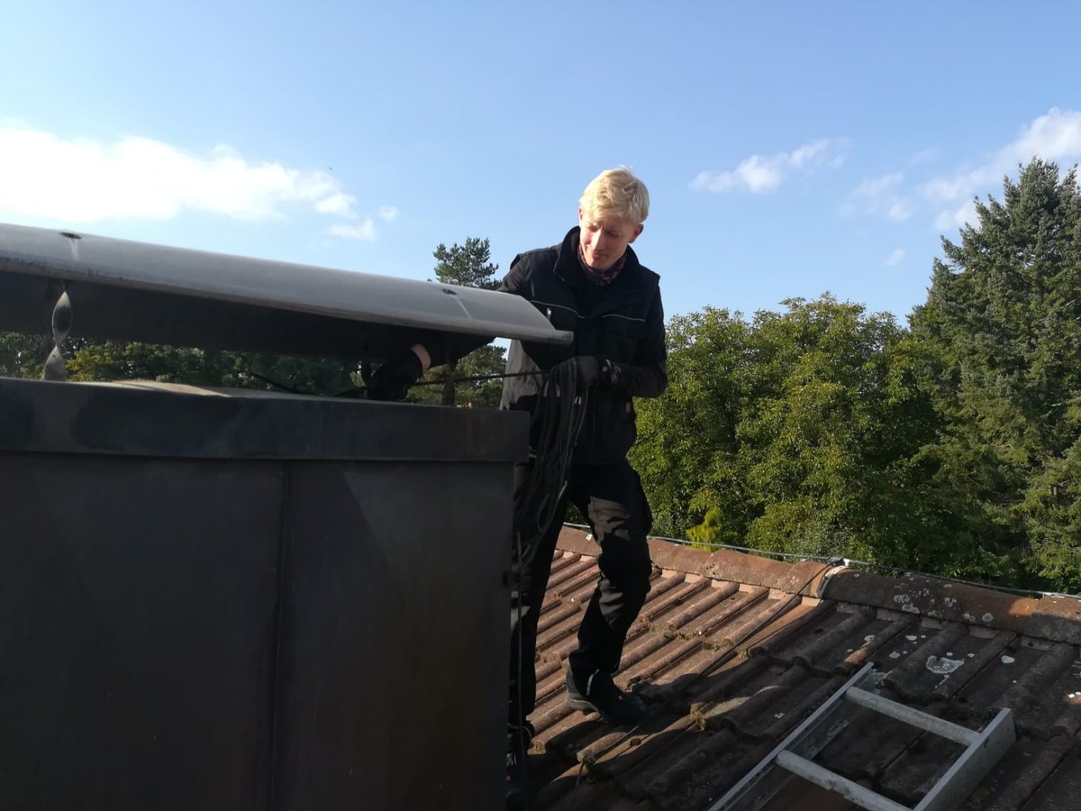 Trainee chimney sweep practicing professional flue-cleaning work