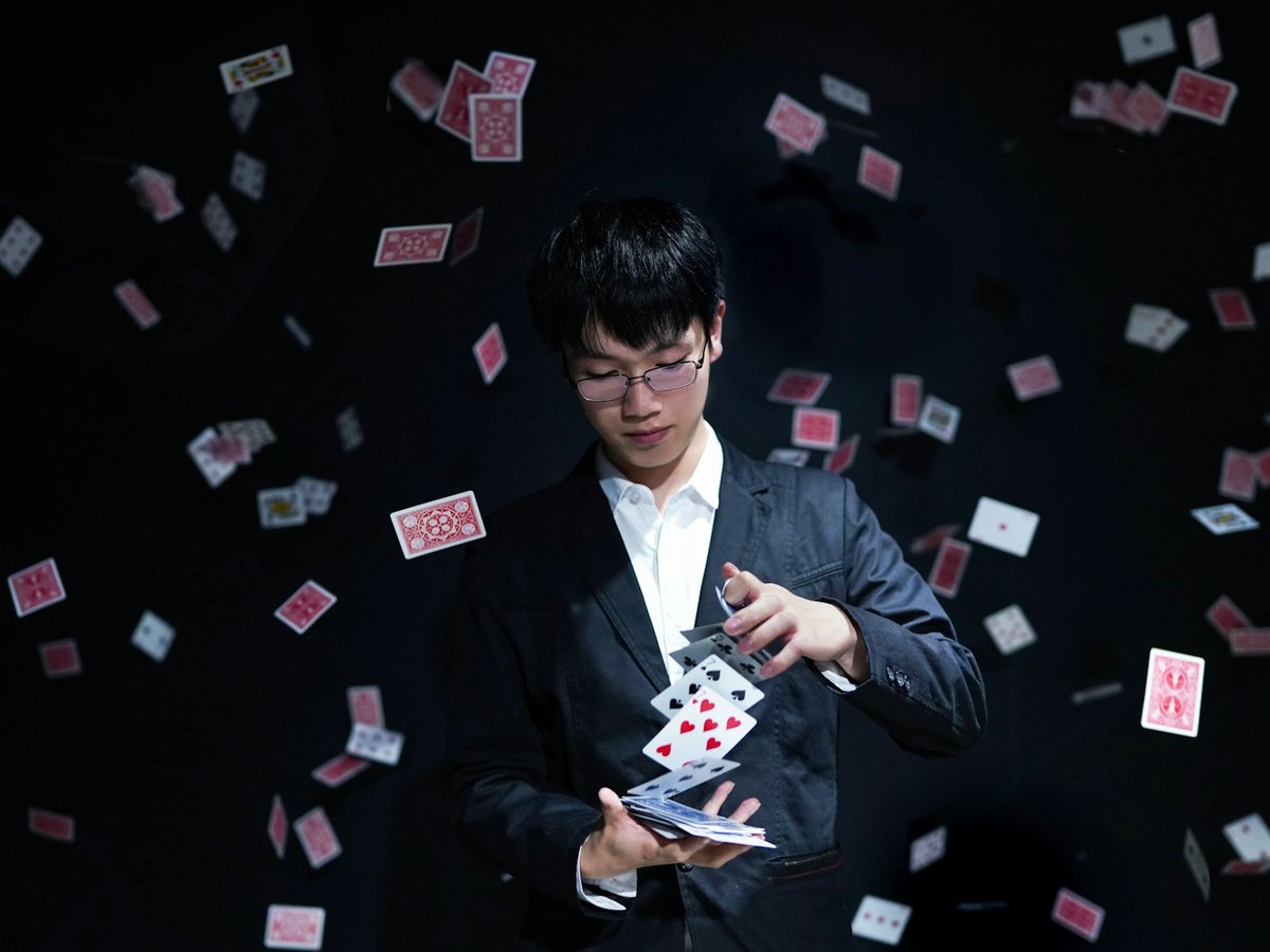 Stage magician performing amid a shower of playing cards