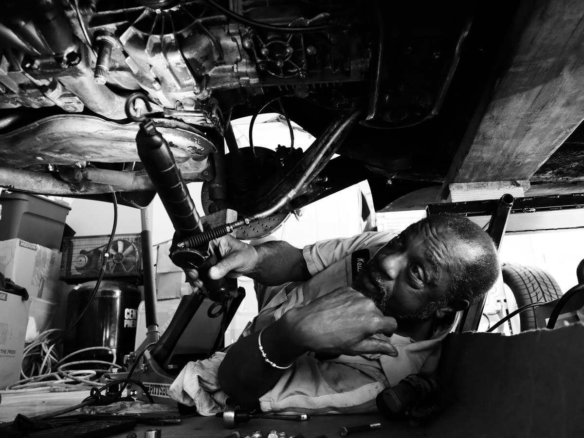 Mechanic repairing a car undercarriage with an impact wrench