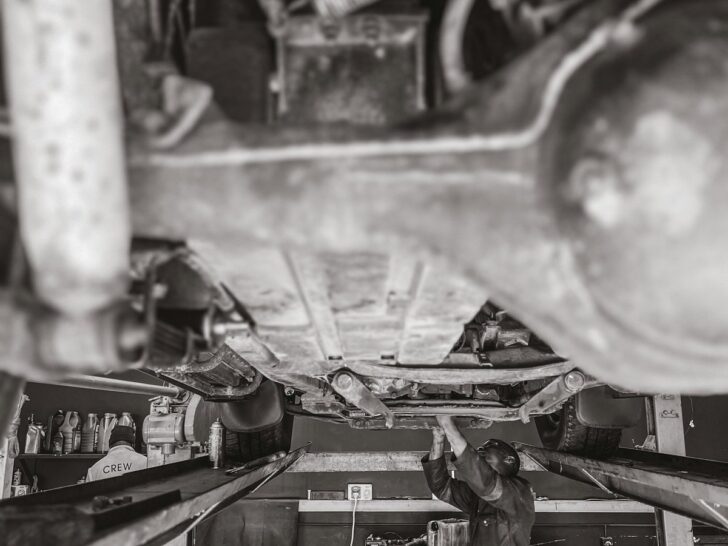 Auto mechanic servicing a vehicle raised on a workshop lift