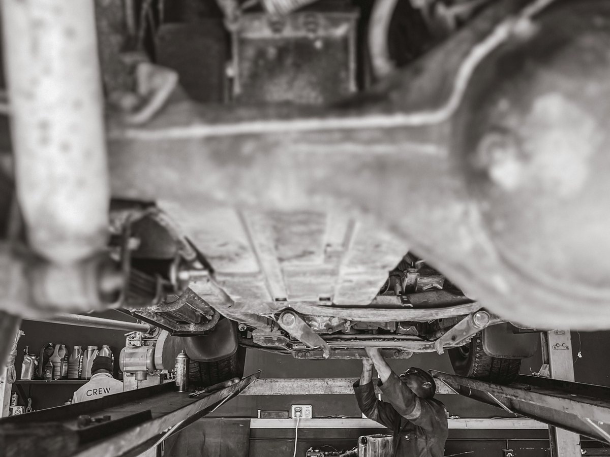 Auto mechanic servicing a vehicle raised on a workshop lift