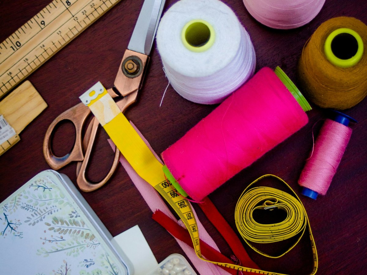 Tailoring tools, measuring tape, thread, and scissors on a worktable
