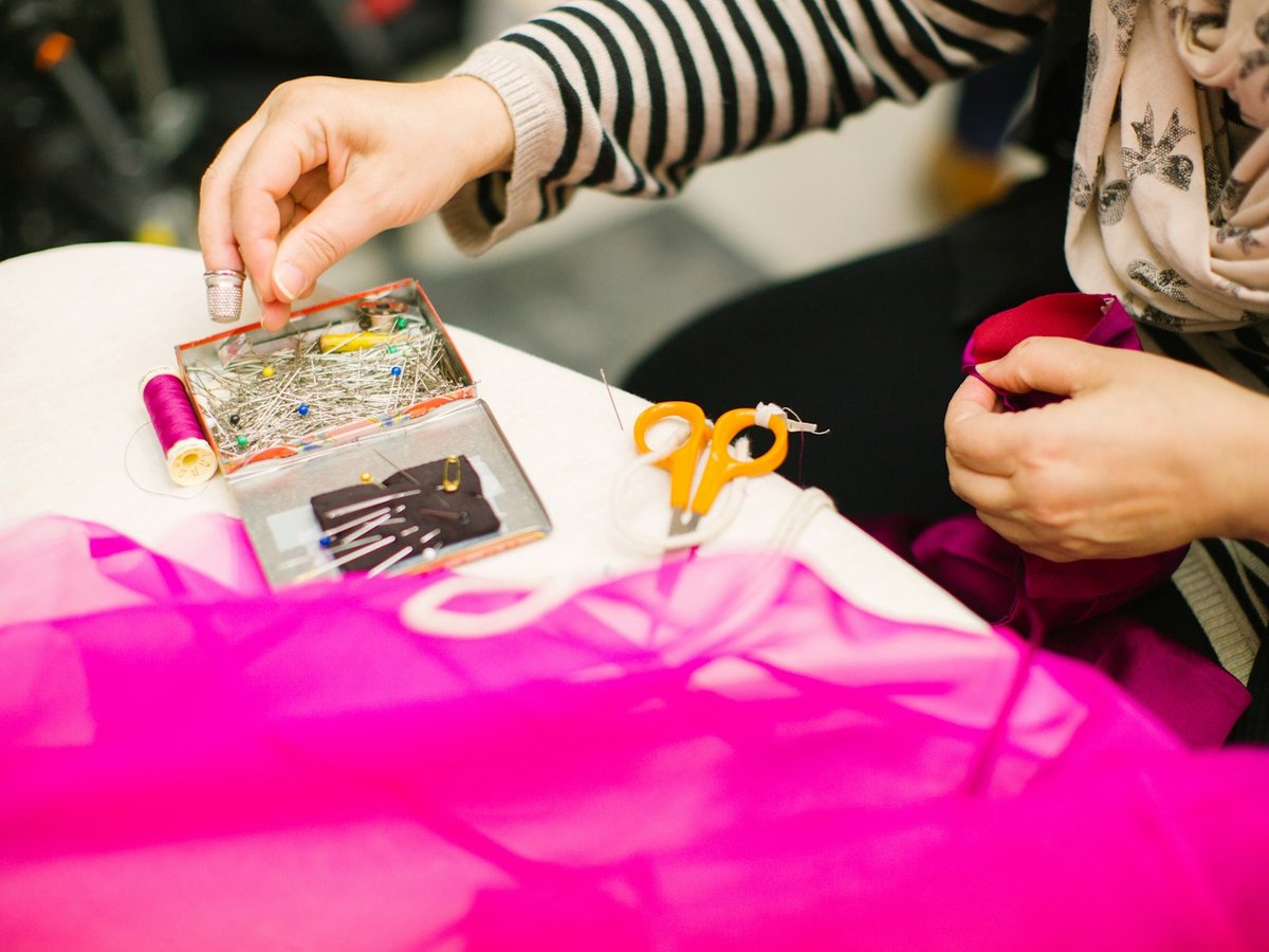 Tailor pinning bright fabric beside sewing supplies
