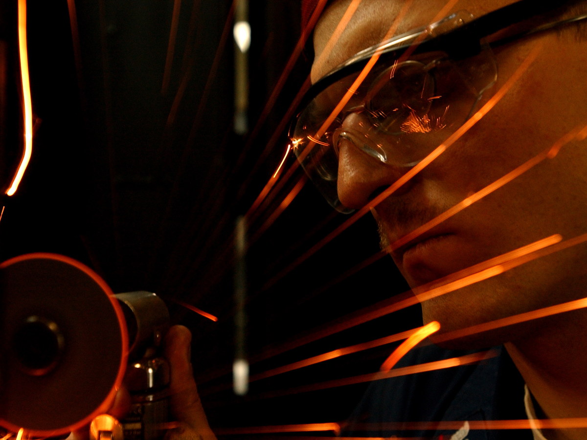 Welder wearing protective gear while bright sparks fly