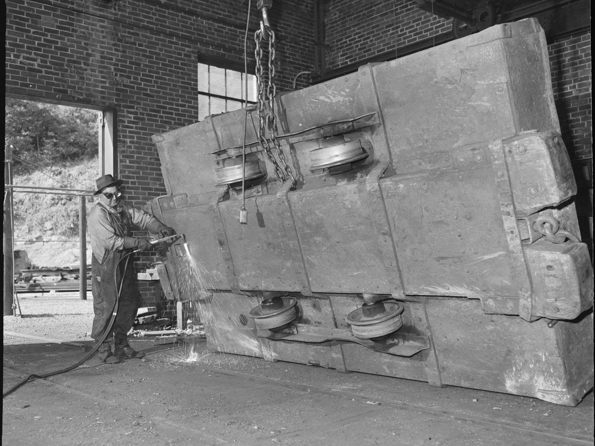 Welder working beside a large industrial metal structure